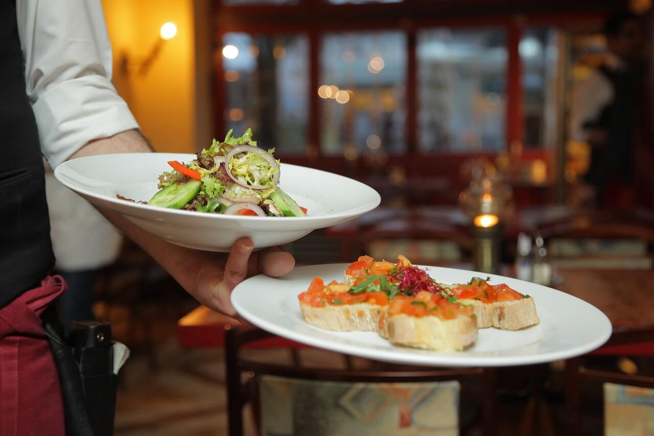 Waiter holding a salad and bruschetta