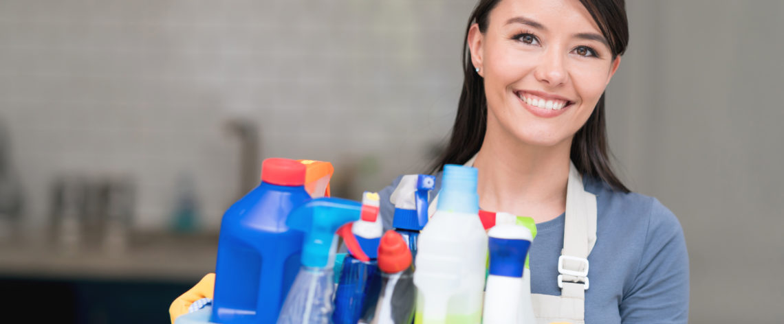Cleaning woman holding tub of cleaning chemicals