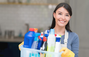 Cleaning woman holding tub of cleaning chemicals