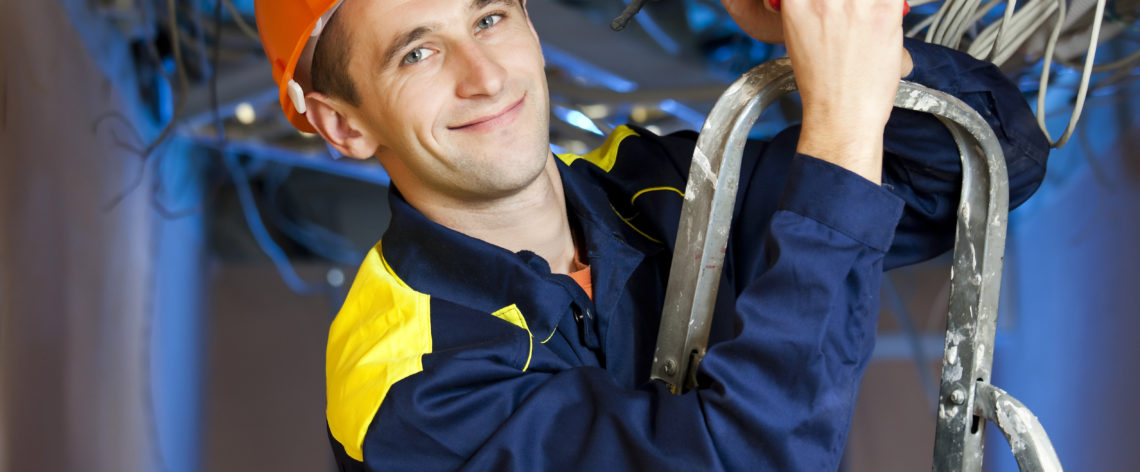 Electrician standing on ladder working on wires