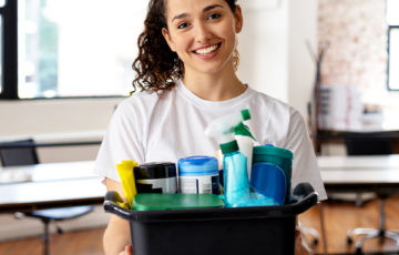 cleaner holding up a box of cleaning tools and chemicals