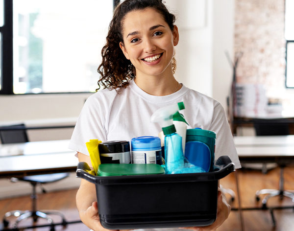 cleaner holding up a box of cleaning tools and chemicals